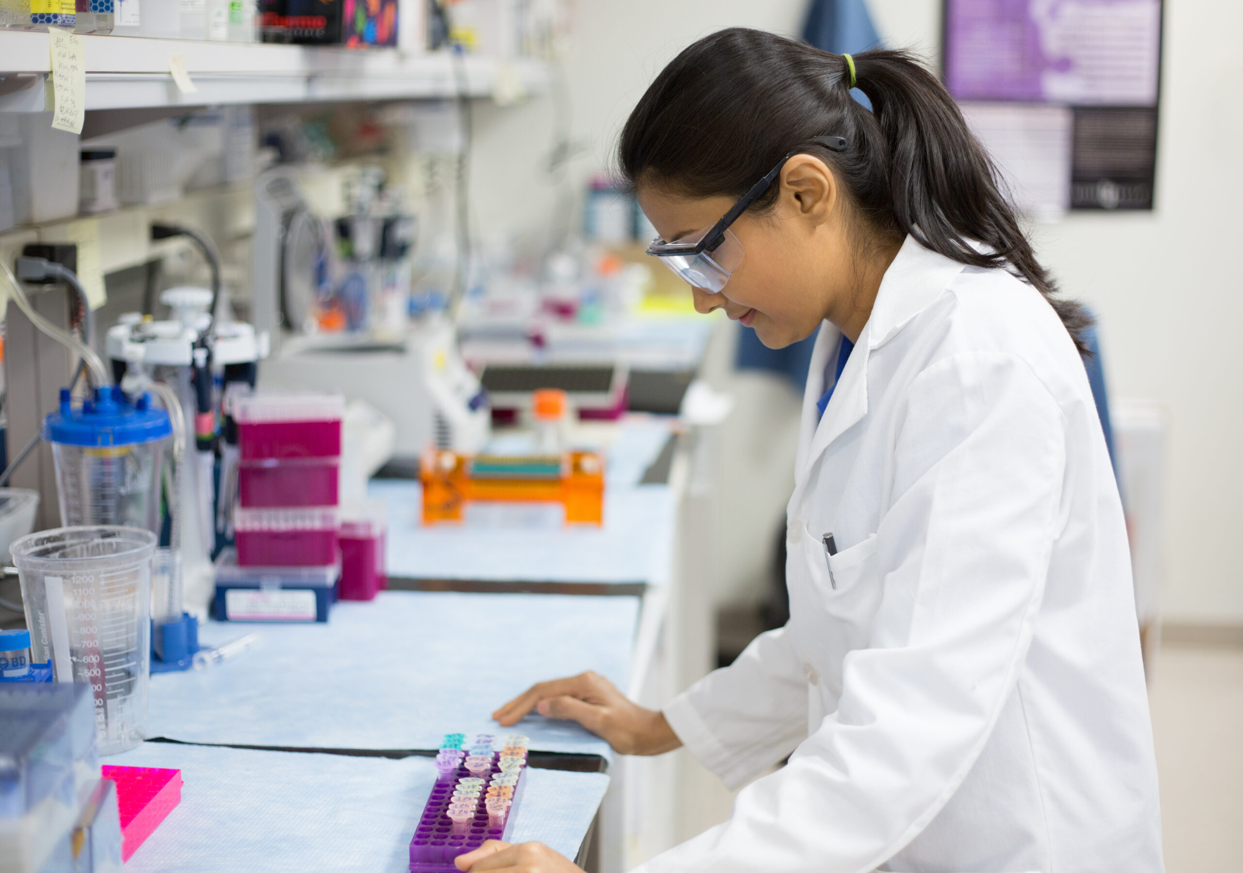 Closeup portrait, young scientist in white labcoat and goggles doing experiments in lab, academic sector.